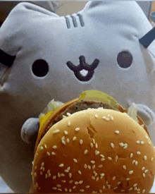a stuffed animal is eating a hamburger with sesame seeds