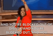 a woman in a red dress is holding a microphone in front of a television and screaming .