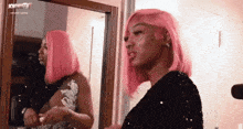 a woman with pink hair is standing in front of a mirror with the word tv on the bottom