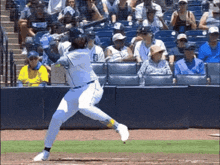 a baseball player is swinging his bat at a ball with a crowd watching