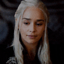 a close up of a woman 's face with blonde hair and a dragon brooch