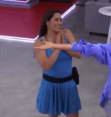 a woman in a blue dress is holding a man 's arm .