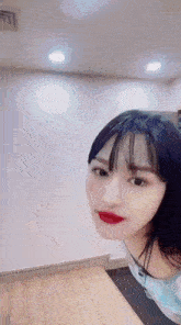 a woman with long black hair and red lipstick is standing in front of a wall .