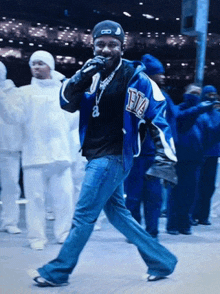 a man wearing a blue jacket with the letter f on it is singing into a microphone