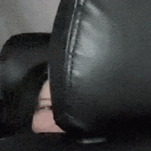 a close up of a person 's face behind a black leather chair .