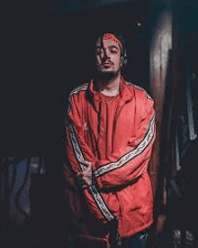 a man wearing a red jacket and a headband is standing in a dark room .