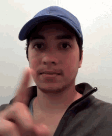 a man wearing a blue hat and a black jacket is making a funny face