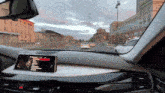 a car is driving down a city street and the dashboard has a phone on it