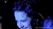 a close up of a woman 's face in a dark room with a blue background .