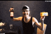 a man in a black tank top is holding a bottle of beer and a piece of cheese