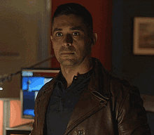 a man wearing a brown leather jacket and black shirt