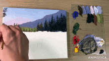 a person is painting a snowy landscape with a palette in the background that says made in animatica