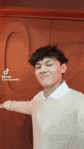 a young man is taking a selfie in front of a wall with a heart on it
