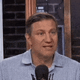 a man wearing a blue shirt is talking into a microphone