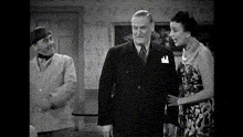 a man in a suit and tie stands next to a woman in a floral dress