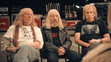 three men are sitting in a circle with one wearing a shirt that says ' rock ' on it