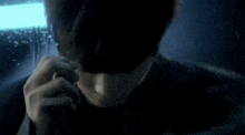 a close up of a man 's face in a dark room with a light behind him .