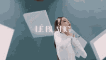 a woman in a white shirt is dancing in front of a wall that says le blanc on it