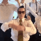 a woman wearing sunglasses and a tie is dancing in a group of men