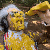 a man with mustard on his face and a bottle of mustard in his hand