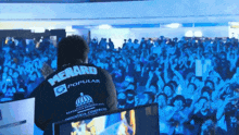 a man stands in front of a crowd wearing a menaro popular shirt