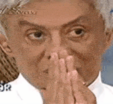 a man is covering his mouth with his hands and making a funny face .