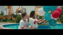 a boy and a girl holding balloons in a pool