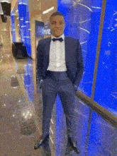 a man in a suit and bow tie is standing with his hands in his pockets .