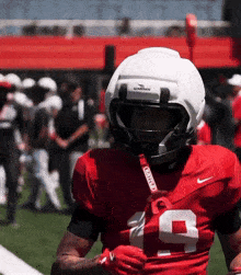 a football player wearing a guardian helmet holds a bat