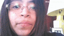 a woman wearing glasses is making a funny face in front of a lamp .