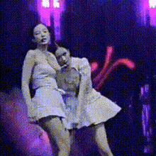 two women in white dresses are dancing on a stage