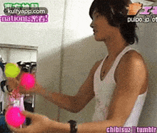 a man in a white tank top is playing with balls .