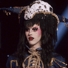 a woman wearing a dalmatian hat with fringe and a rope around her neck