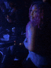 a woman with purple hair is sitting at a table in a club .