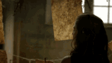 a woman is standing in a dark room looking at a piece of paper hanging on a clothesline .