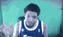 a man wearing a blue adidas jersey waves his hand