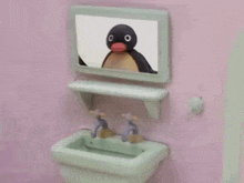 a penguin is looking at himself in a mirror in a bathroom sink .