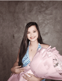 a woman in a blue and white dress is holding a large pink bouquet of flowers