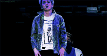 a man with white hair is dancing on a stage while another man watches .
