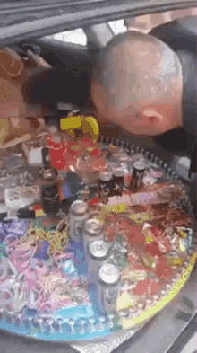 a man is sitting in the back of a car surrounded by cans and bottles .