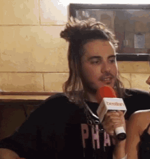 a man with long hair is holding a microphone and wearing a black shirt that says pha