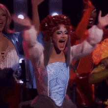 a woman with red hair and a blue top is dancing