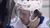 a hockey player wearing a white helmet with bauer written on it