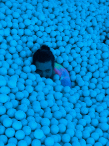 a man is laying in a pool of blue balls