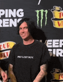 a man wearing a pro lost boy shirt stands in front of a monster energy sign