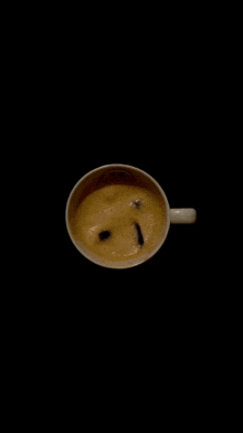 a cup of coffee on a black background with a swirl of milk