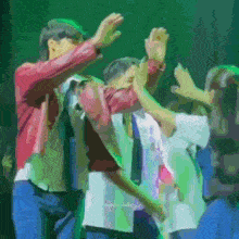 a group of people are dancing on a stage with their hands in the air .