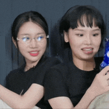 a woman wearing glasses and a black shirt is sitting next to another woman