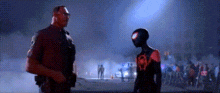 a police officer and a spider-man are standing next to each other in a dark room .