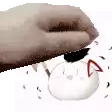 a hand is holding a white ball with a red nose and a black tail .